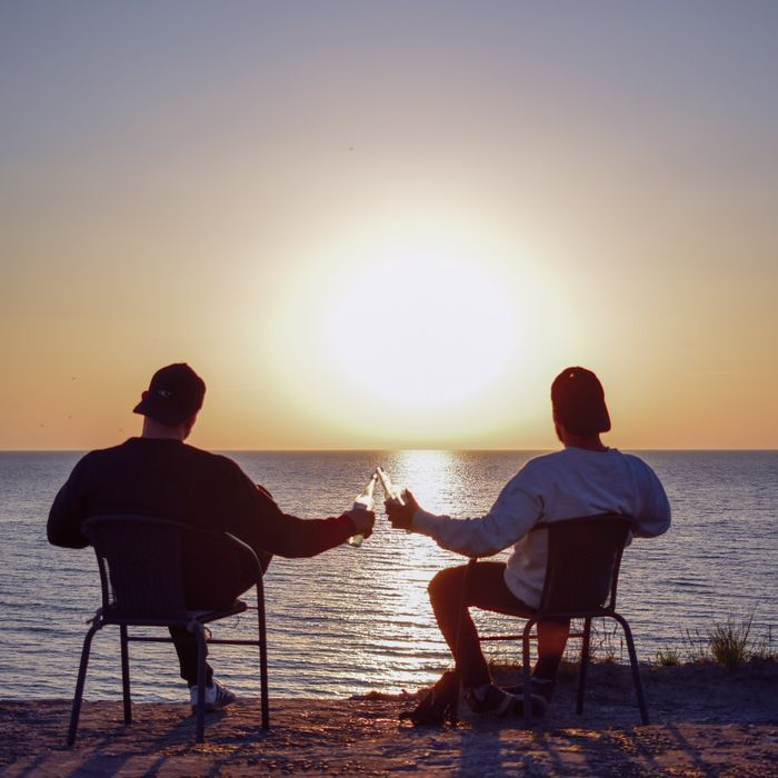 Two people enjoying a sunset toast by the ocean. Perfect relaxation moment.